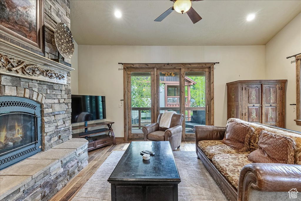 Living area with wood finished floors, a ceiling fan, a stone fireplace, and recessed lighting
