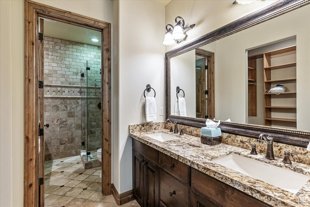 Bathroom with double vanity, a shower stall, and toilet