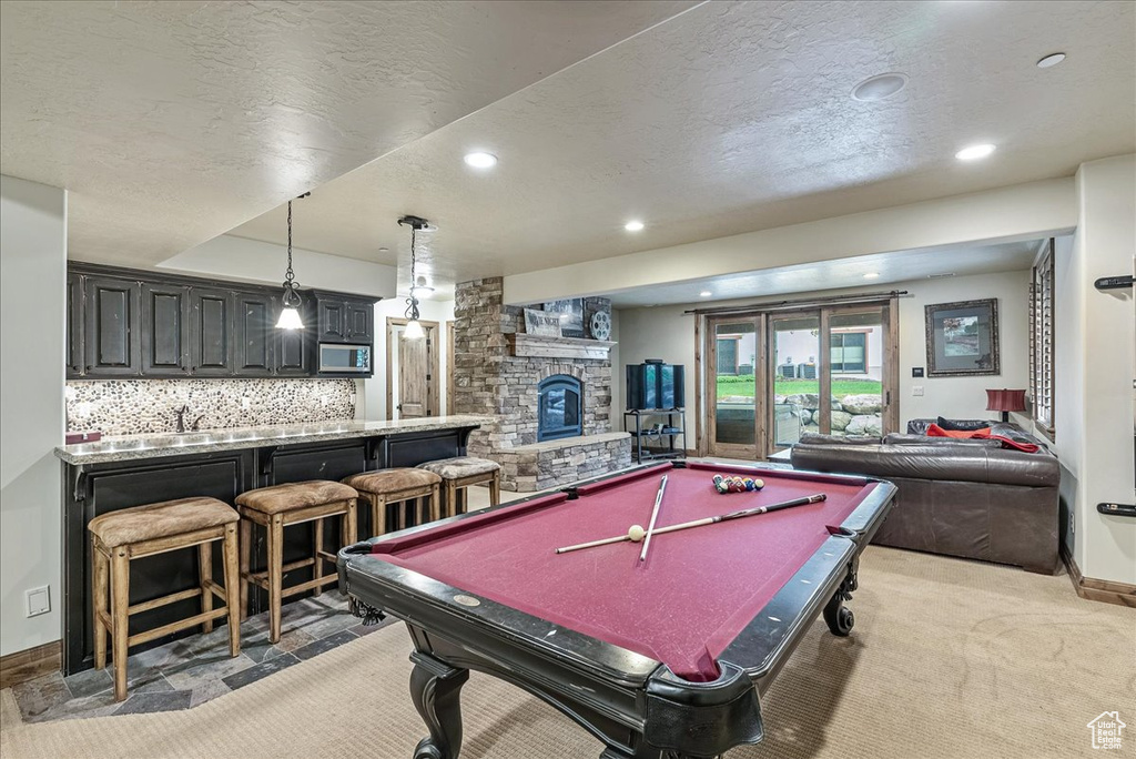 Game room with wet bar, a fireplace, light carpet, recessed lighting, and a textured ceiling