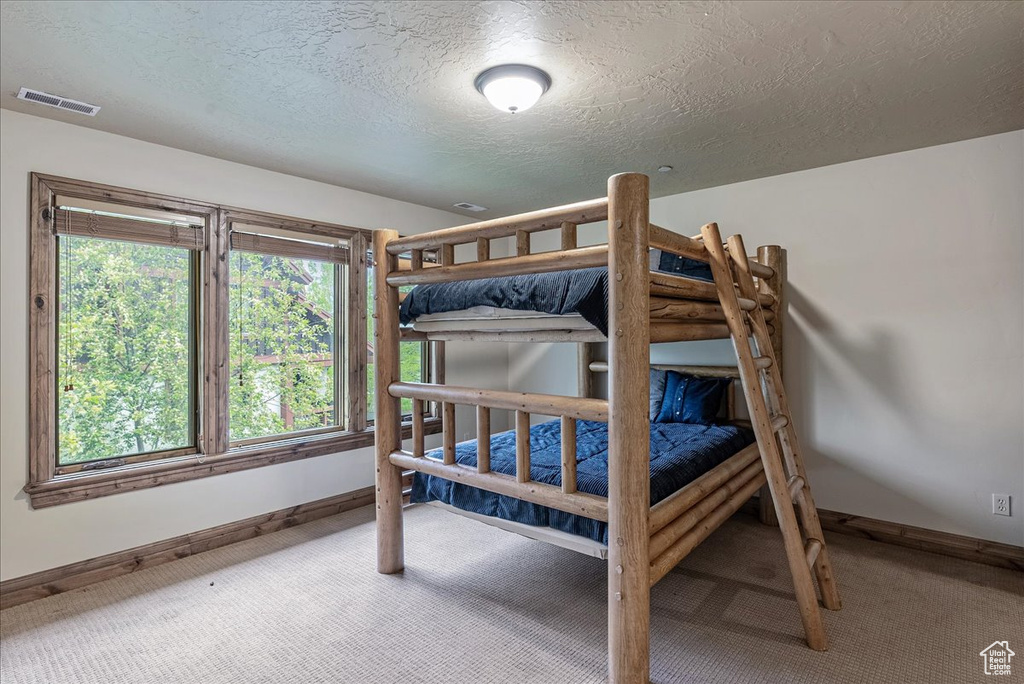 Bedroom with carpet flooring, baseboards, and a textured ceiling