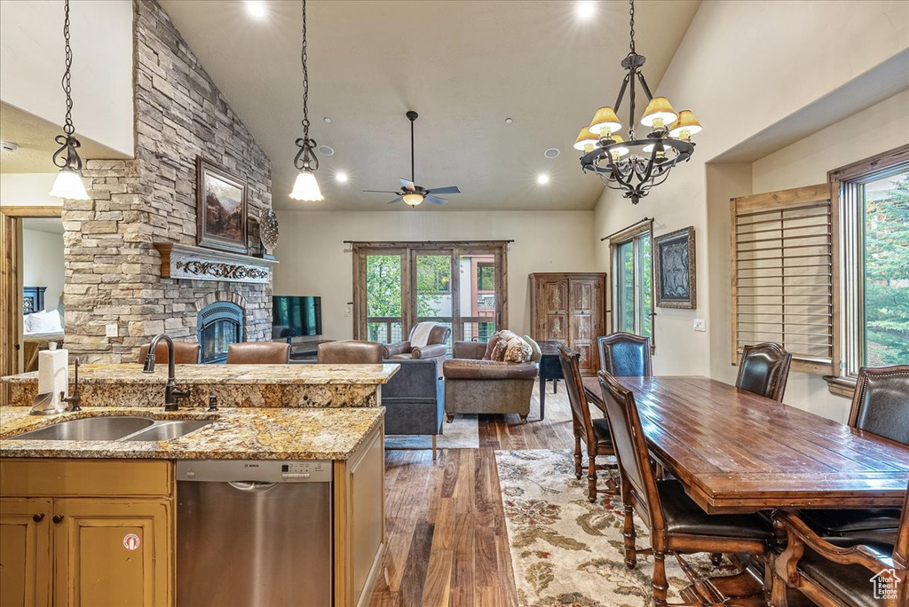 Kitchen with stainless steel dishwasher, a sink, high vaulted ceiling, open floor plan, and light wood-style floors