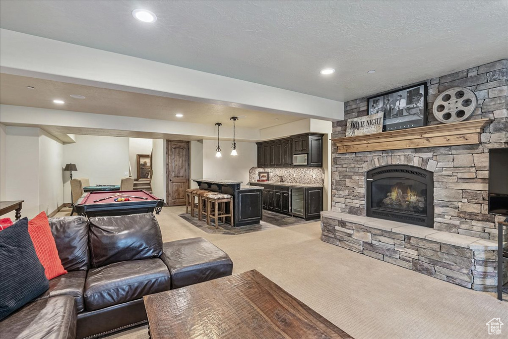Living room featuring bar with sink, pool table, light carpet, a stone fireplace, and recessed lighting