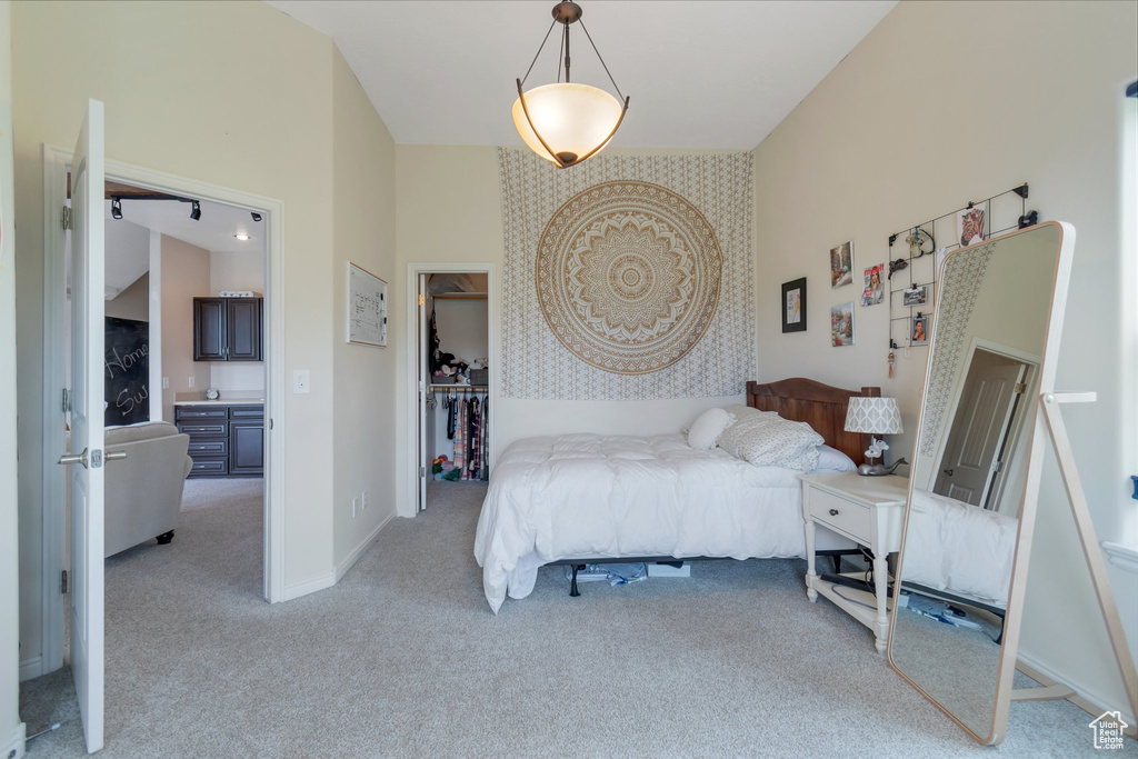 Bedroom featuring light colored carpet, baseboards, a walk in closet, and a closet