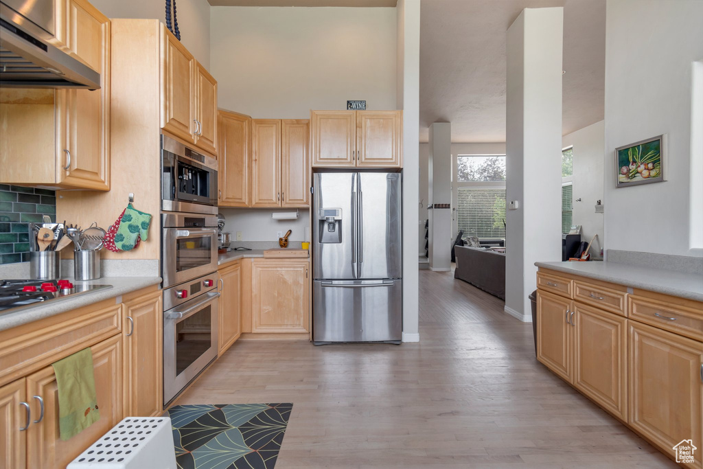 Kitchen featuring under cabinet range hood, appliances with stainless steel finishes, light wood-style floors, and light brown cabinetry