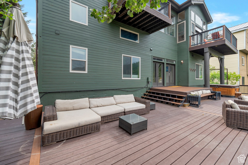 Wooden deck with a hot tub and an outdoor hangout area