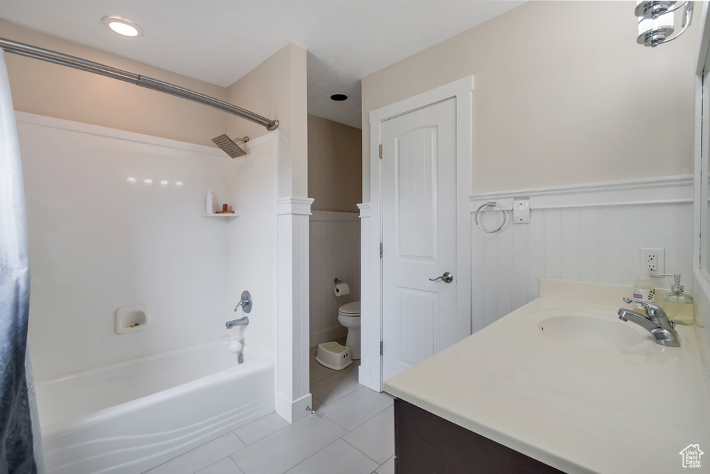 Full bath featuring a wainscoted wall, tile patterned floors, bathing tub / shower combination, toilet, and vanity