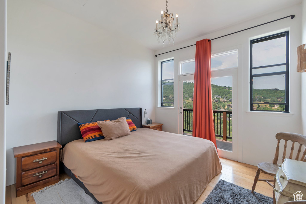 Bedroom featuring an inviting chandelier, access to outside, and light wood-type flooring