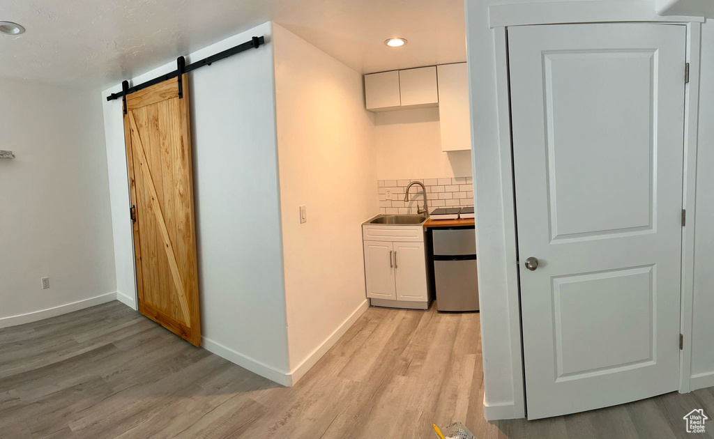Kitchen with a sink, white cabinets, light wood-style floors, and recessed lighting