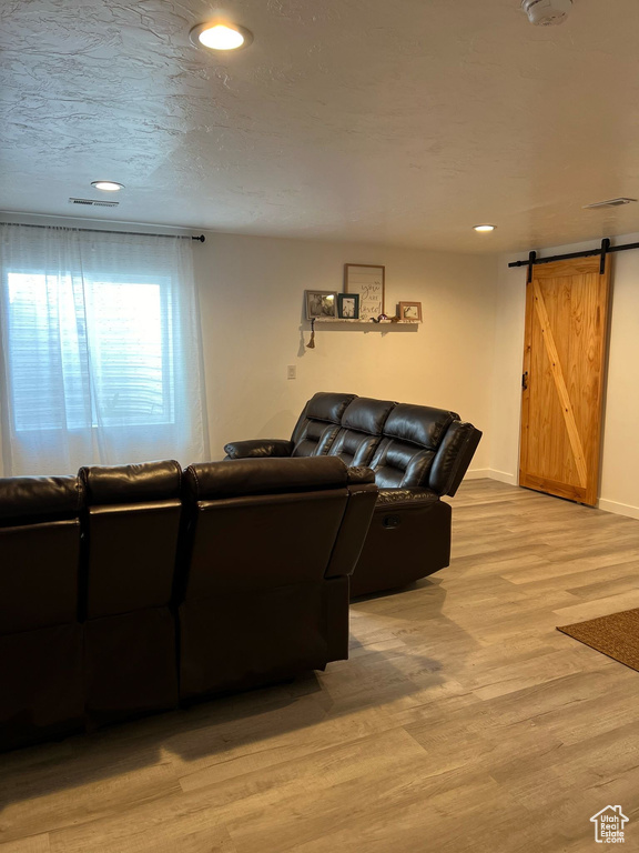 Living area with a barn door, light wood-style floors, baseboards, and recessed lighting