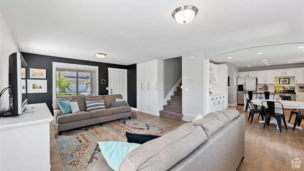 Living area featuring recessed lighting, stairs, light wood-style floors, and baseboards