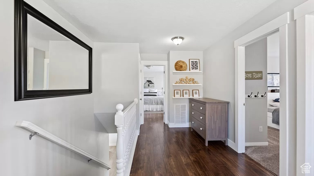 Hall featuring baseboards, an upstairs landing, and dark wood-type flooring