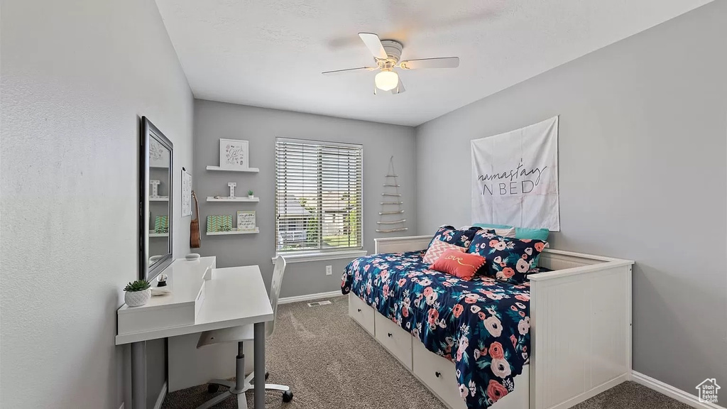 Carpeted bedroom with ceiling fan and baseboards