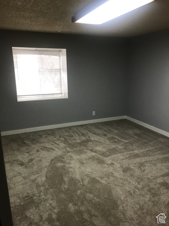 Unfurnished room with dark carpet and baseboards