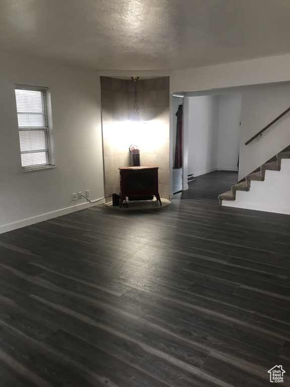 Unfurnished living room with baseboards, a textured ceiling, stairs, and dark wood finished floors