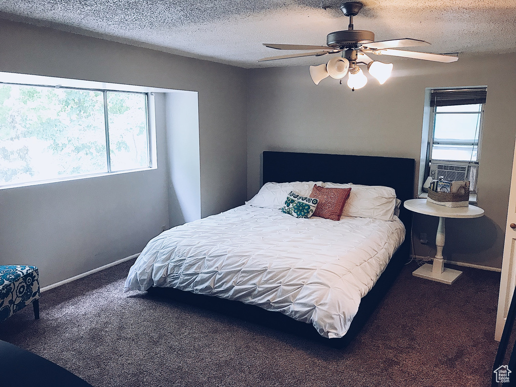 Carpeted bedroom featuring baseboards, a textured ceiling, a ceiling fan, and cooling unit