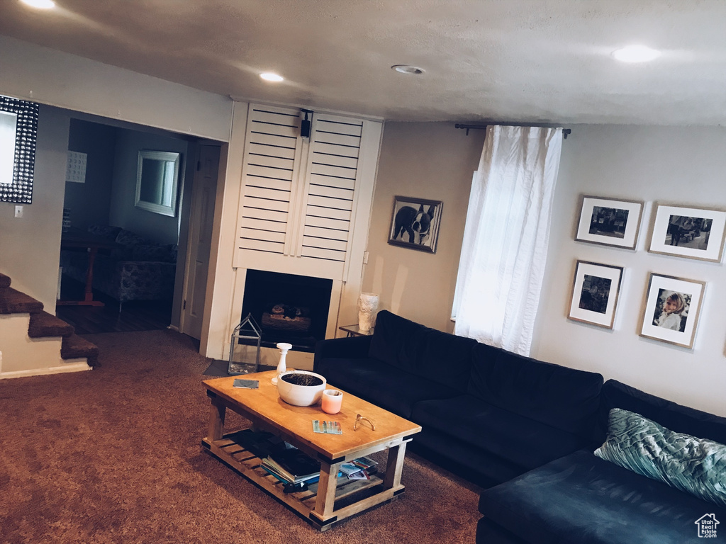 Carpeted living area featuring stairway, a fireplace, and recessed lighting