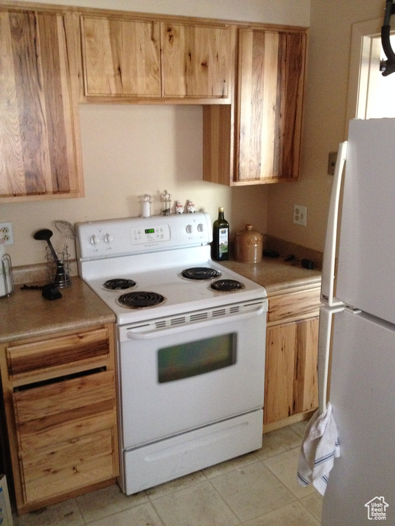 Kitchen with light countertops, white appliances, and light tile patterned floors