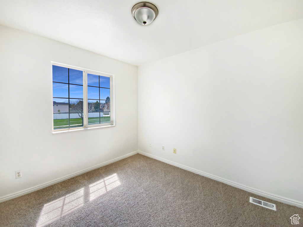 Carpeted spare room with visible vents and baseboards