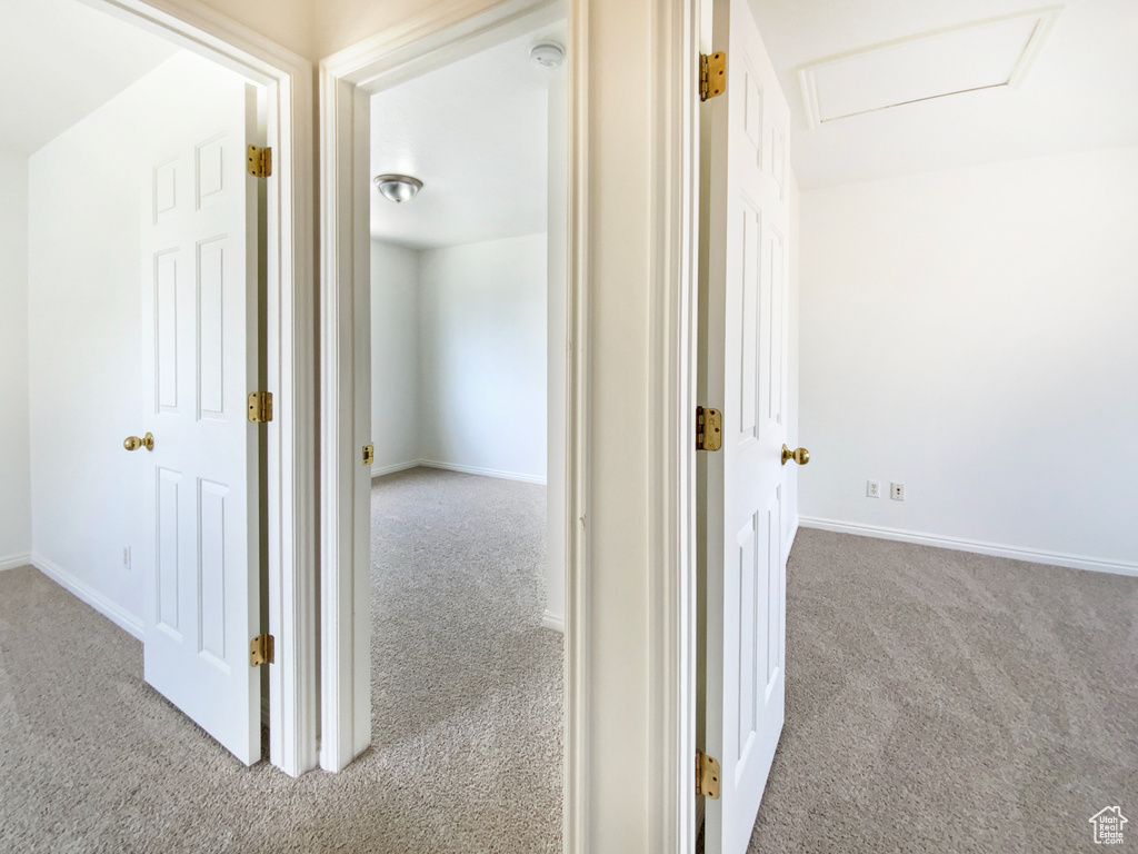 Hall featuring attic access, baseboards, and carpet flooring