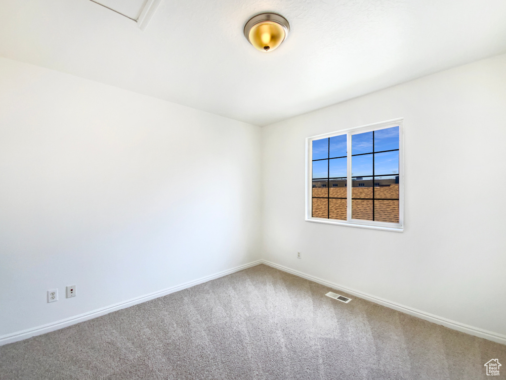 Empty room featuring carpet floors, visible vents, and baseboards