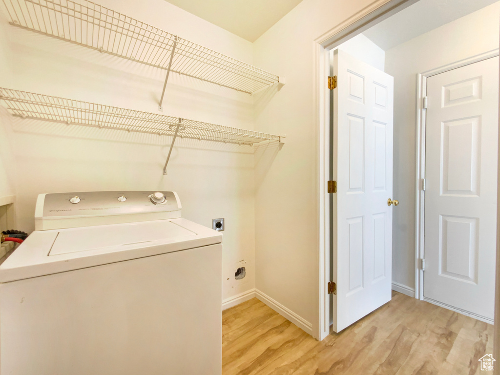 Washroom with light wood-type flooring, baseboards, laundry area, and washer / clothes dryer