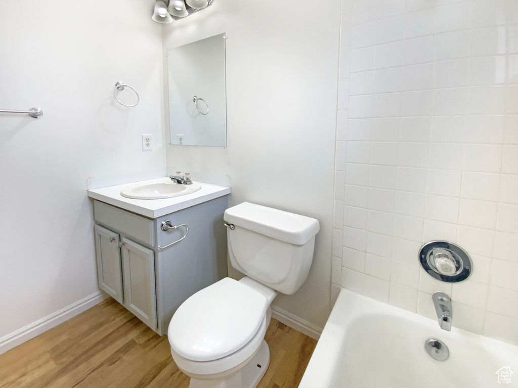 Bathroom with toilet, vanity, wood finished floors, and baseboards