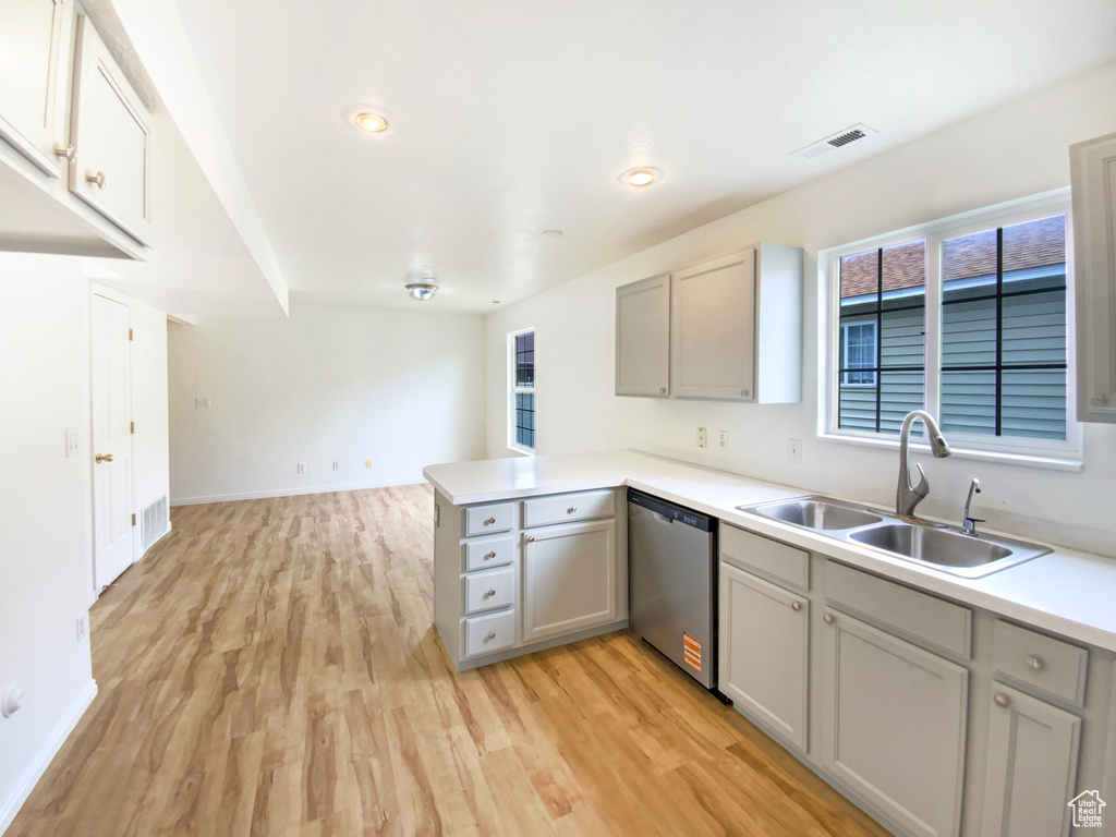Kitchen with light wood-style flooring, a sink, visible vents, gray cabinets, and dishwasher