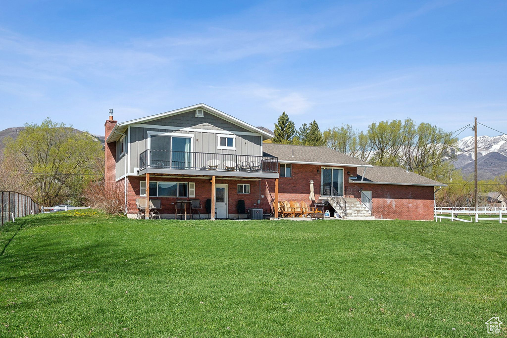 Back of property featuring a chimney, brick siding, fence, and a lawn