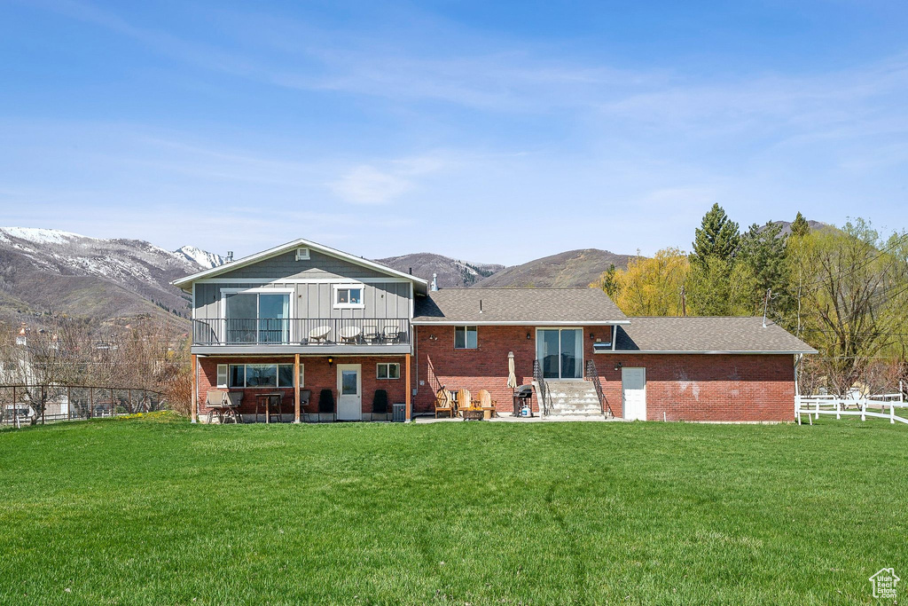 Back of property featuring brick siding, a mountain view, and a yard