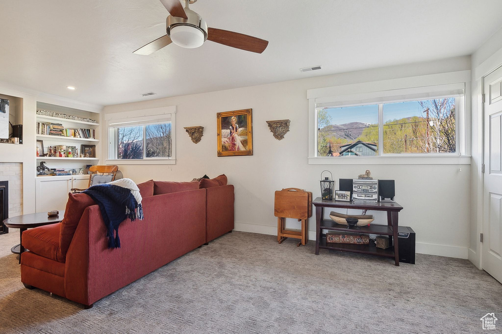 Carpeted living room featuring a fireplace, visible vents, a ceiling fan, and baseboards