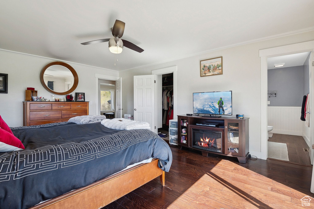 Bedroom with wainscoting, ensuite bath, wood finished floors, and a closet