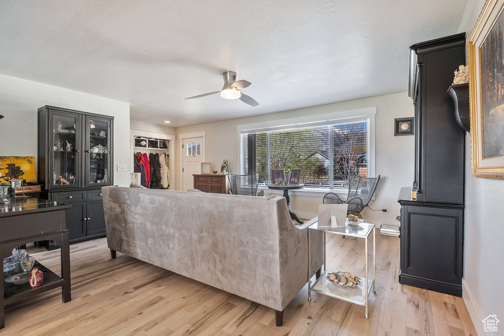 Living area featuring baseboards, a ceiling fan, and light wood-style floors