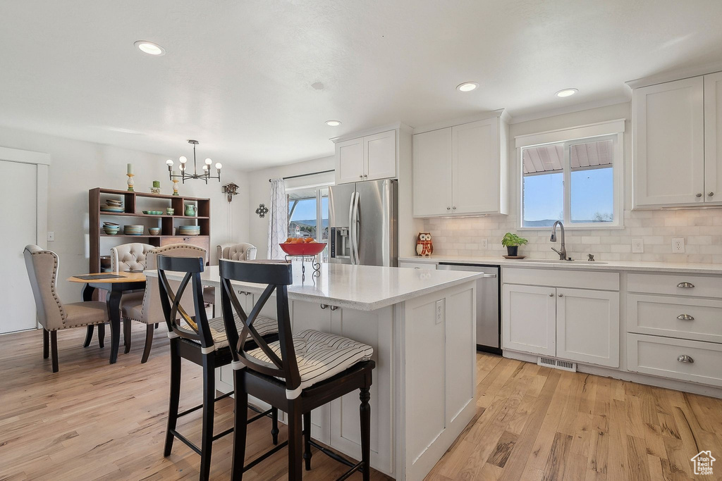 Kitchen featuring a kitchen breakfast bar, a sink, stainless steel appliances, light countertops, and visible vents