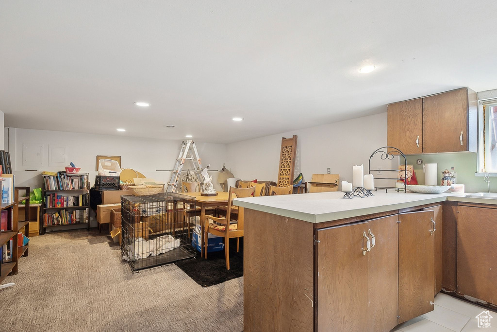 Kitchen with brown cabinetry, light countertops, recessed lighting, and a peninsula