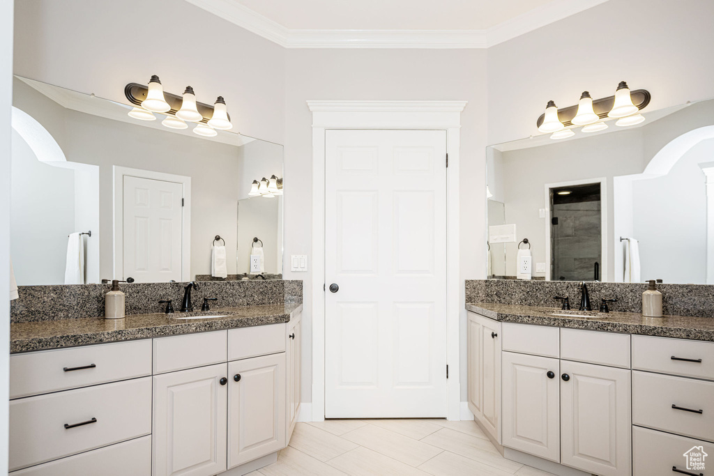 Full bathroom with two vanities, crown molding, a sink, and a stall shower