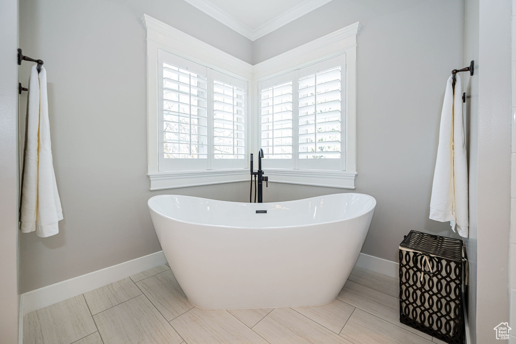 Bathroom featuring a freestanding bath, baseboards, and ornamental molding