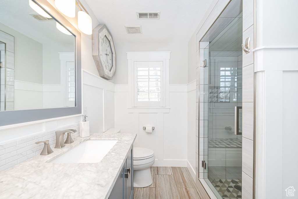 Bathroom with toilet, wainscoting, visible vents, a shower stall, and vanity