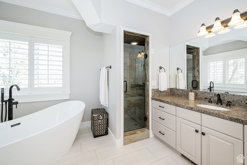 Full bath with a soaking tub, a stall shower, baseboards, crown molding, and vanity