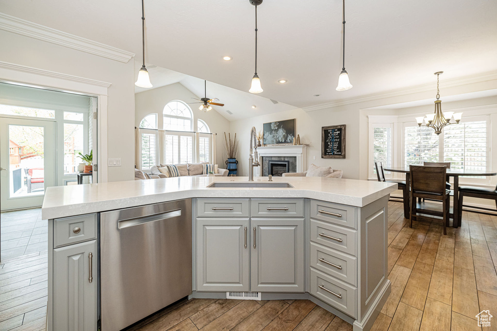 Kitchen with a sink, open floor plan, dishwasher, a fireplace, and gray cabinetry
