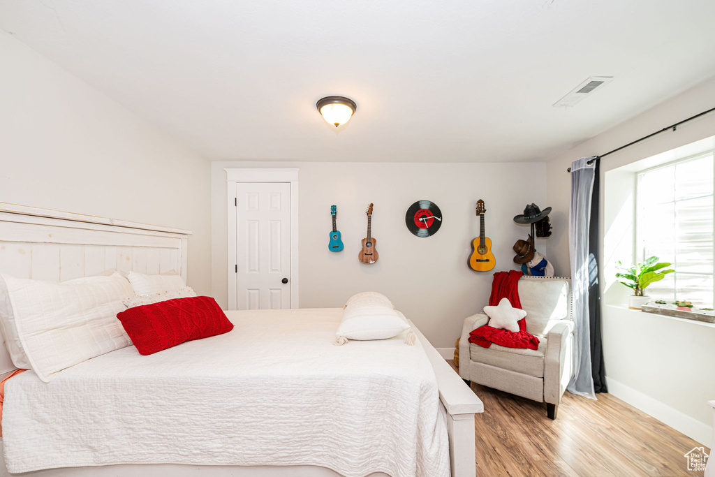 Bedroom with wood finished floors, visible vents, and baseboards