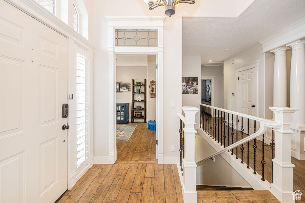 Entryway with baseboards, a chandelier, and light wood-style flooring
