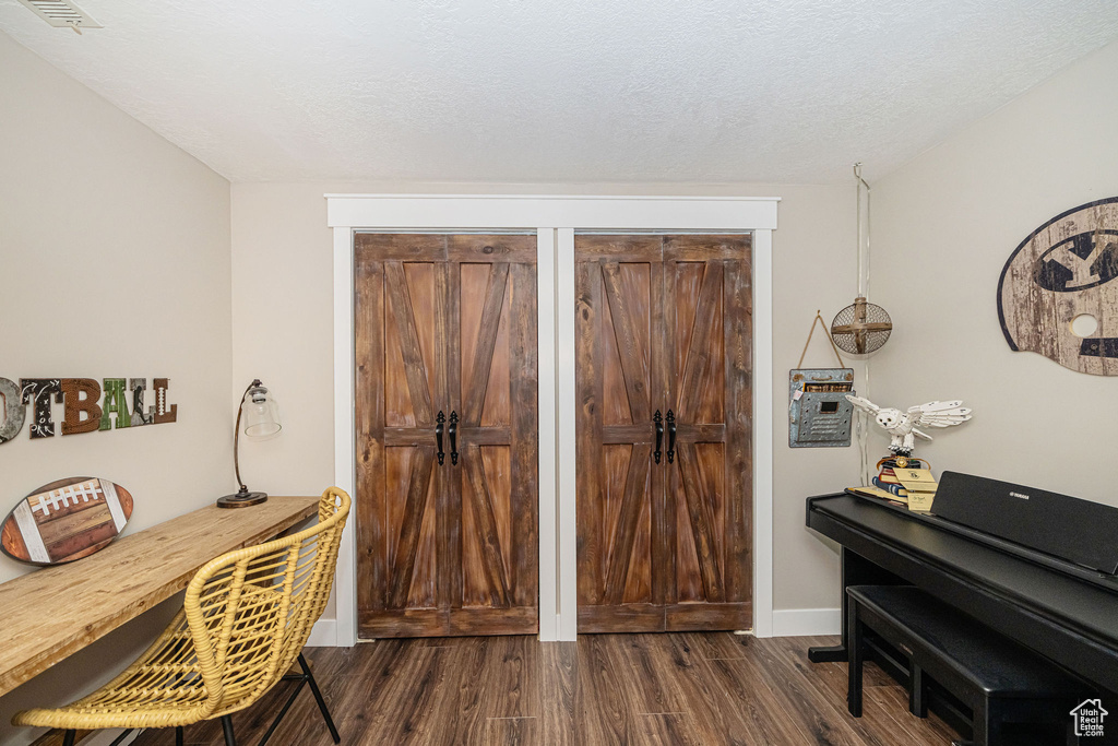 Office featuring baseboards, visible vents, a textured ceiling, and dark wood-style floors