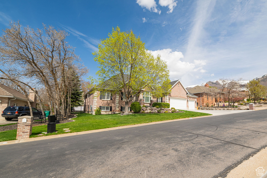 View of front of house featuring a garage, a residential view, a front yard, and concrete driveway