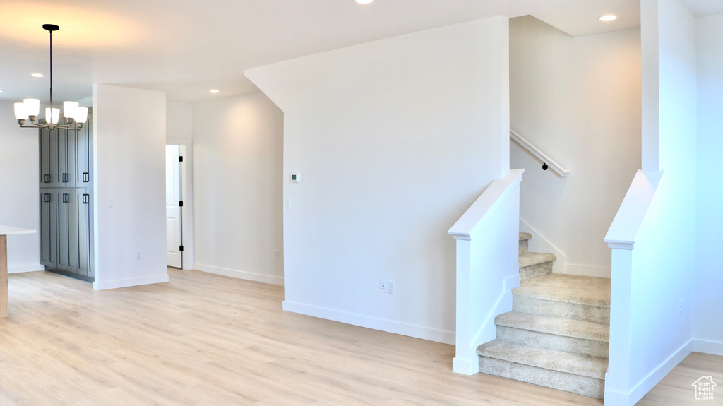 Stairway featuring baseboards, wood finished floors, recessed lighting, and a notable chandelier