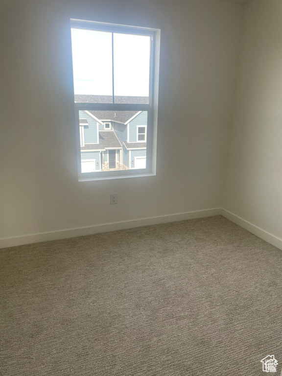 Carpeted spare room featuring baseboards