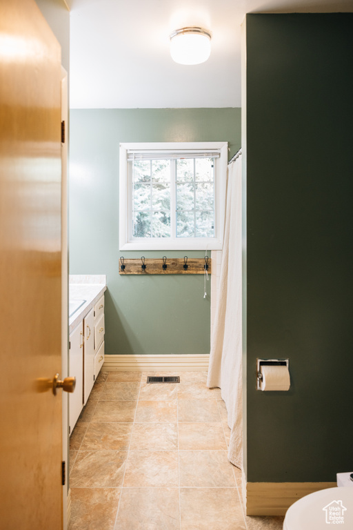 Bathroom with baseboards, vanity, tile patterned floors, and visible vents