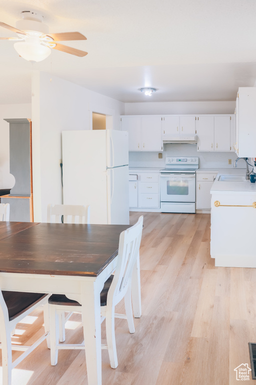 Kitchen with a sink, white appliances, ceiling fan, light countertops, and under cabinet range hood