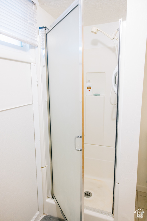 Bathroom with baseboards, tile patterned flooring, and a shower stall