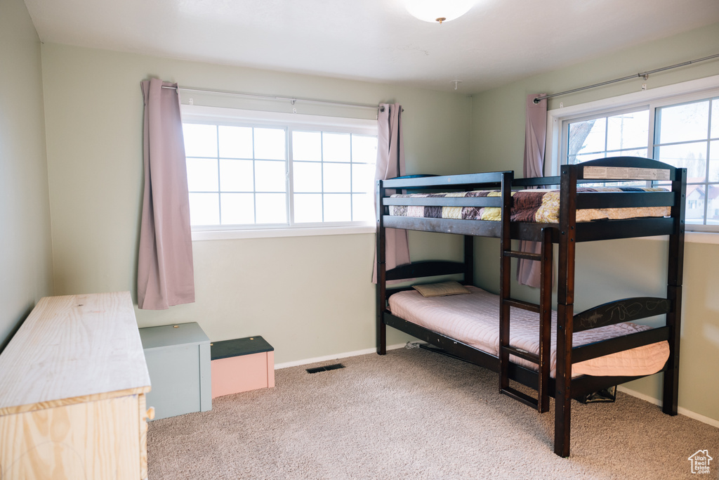 Carpeted bedroom featuring baseboards and multiple windows