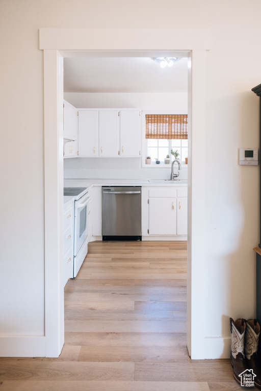 Kitchen featuring white cabinets, stainless steel dishwasher, a sink, light countertops, and white range with electric cooktop